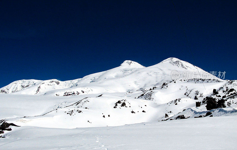 以深蓝色天空为背景的厄尔布鲁斯山的山峰。积雪盖顶的高加索山脉。