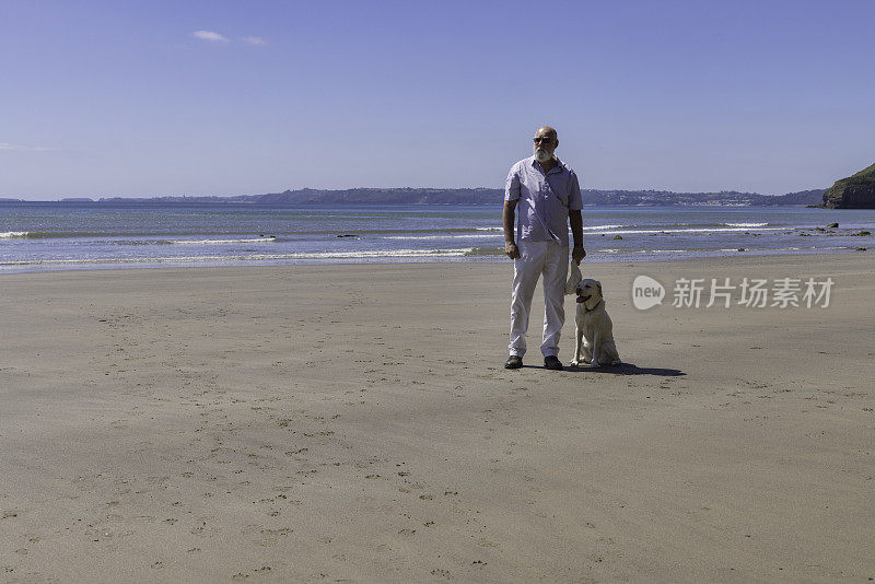 一名男子和他的狗在西威尔士的海滩上