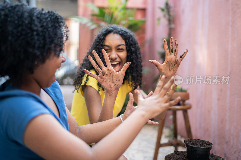 快乐的姐妹们在家里种完花后双手沾满了泥巴