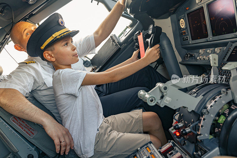 小男孩戴着飞行员帽坐在驾驶舱里