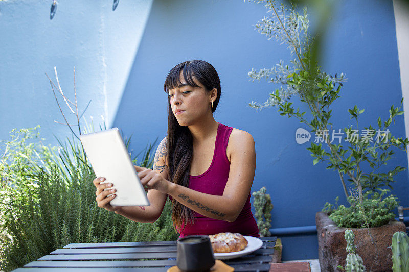 年轻女子一边喝咖啡一边用笔记本电脑工作