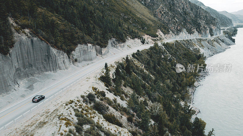 深灰色的汽车在山间的狭窄道路上行驶。无人机视频