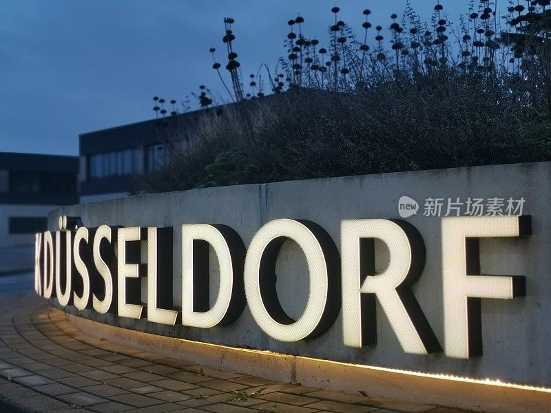 “Düsseldorf”这个字被人工照明，安装在一个环形路口的混凝土墙上