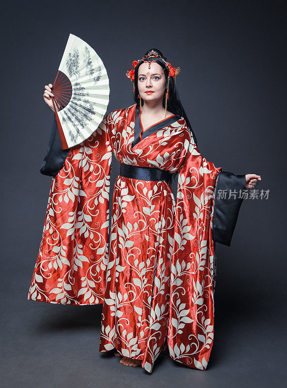 美丽的年轻女子，穿着红色的中国传统服装，手扇