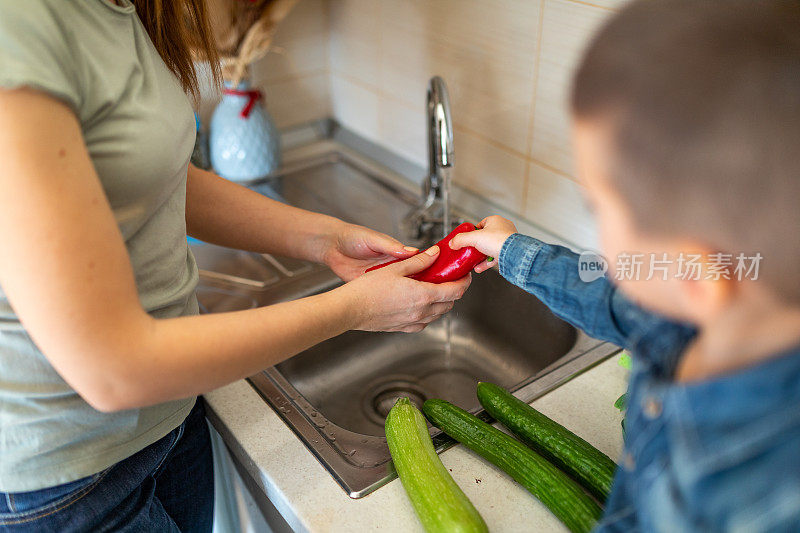 男孩在厨房帮助妇女洗菜