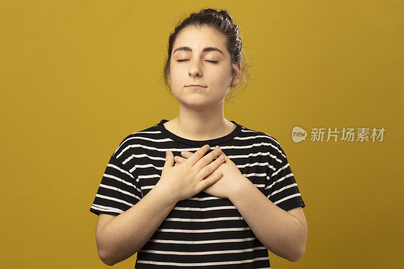 年轻女子站在画室里，手牵着手祈祷。合十礼