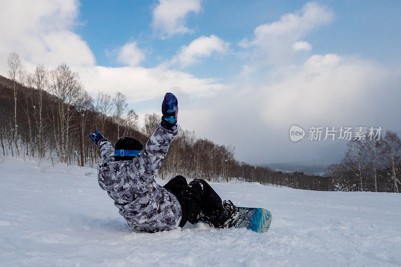 青少年滑雪板坐在滑雪斜坡上举起手