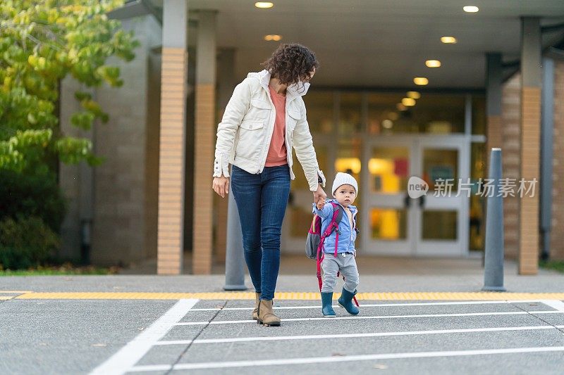 妈妈带着蹒跚学步的女儿放学回家