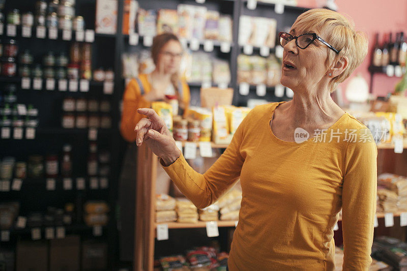 一位年长女性在有机食品店挑选要买的东西。