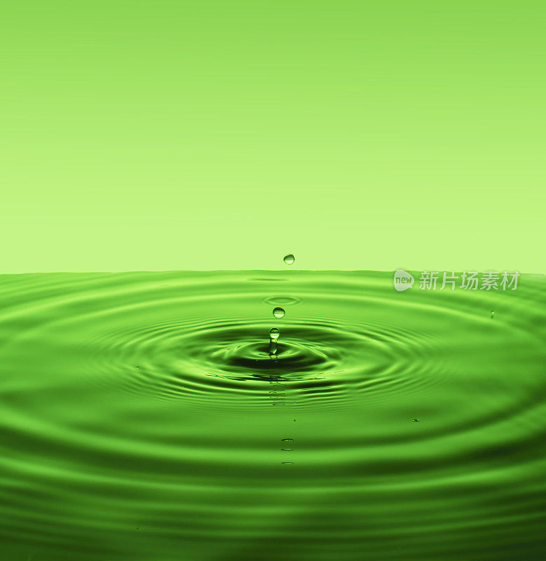 绿色背景与发散的圆圈从水滴表面的水。