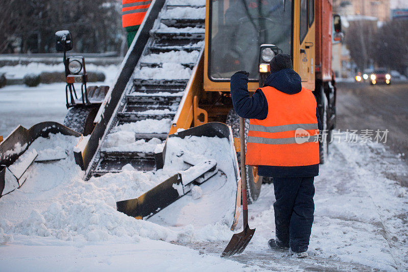 拖拉机正在清扫道路上的积雪。挖掘机清理城市街道上的大量积雪。工人们在冬天清扫道路上的积雪，清扫道路上的暴风雪