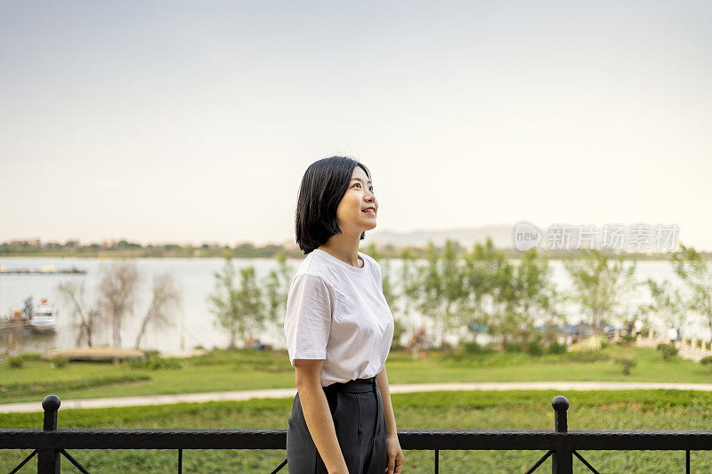 一位亚洲妇女在美丽的河边眺望远方