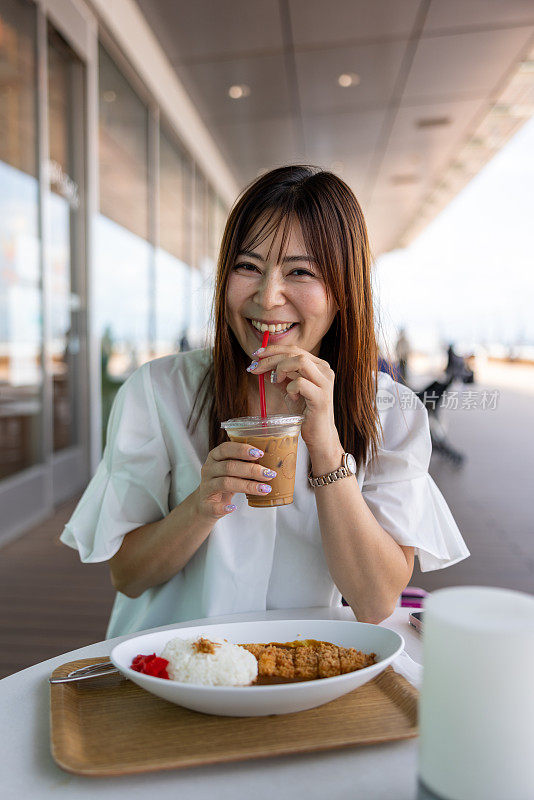 在户外咖啡馆喝一杯冰咖啡的女人