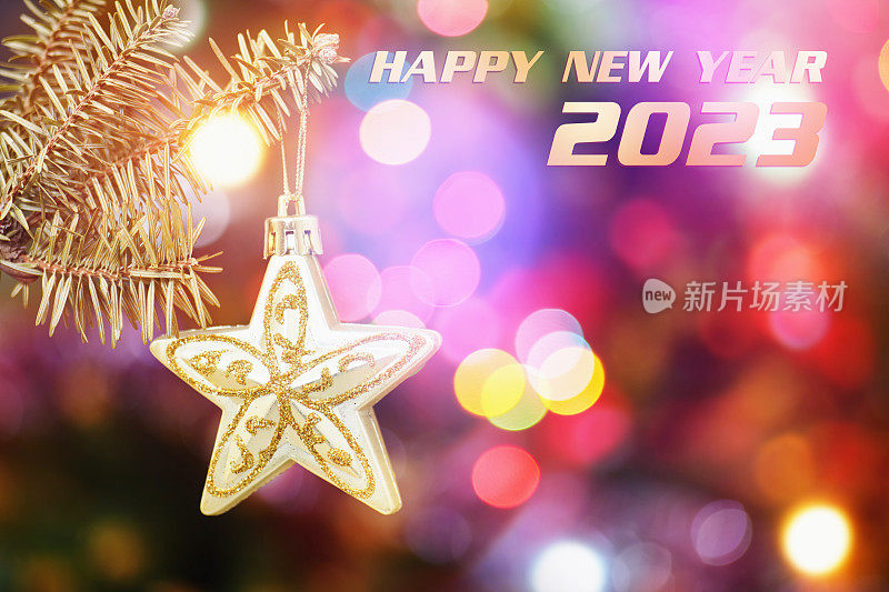 2023年装饰拜年。悬挂在树枝上的装饰明星和圣诞树在模糊的彩色背景下的装饰品