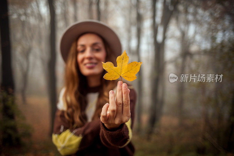 美丽的年轻女子在秋天走在户外的画像