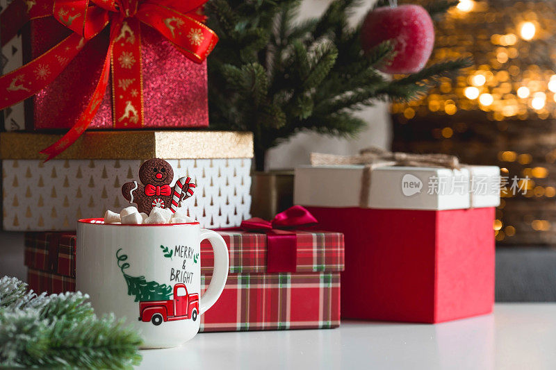 礼品盒、一杯热可可、棉花糖和一个姜饼人放在客厅室内的桌子上。2023年圣诞和冬季假期的温馨概念。
