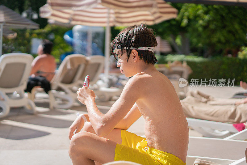小男孩在度假村的游泳池里吃蛋筒冰淇淋
