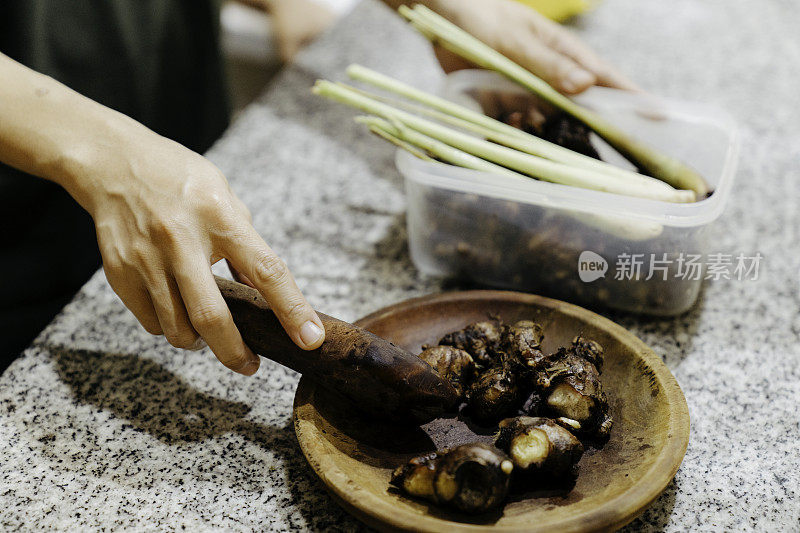 特写妇女在厨房剥大蒜(用新鲜原料制作健康食品)