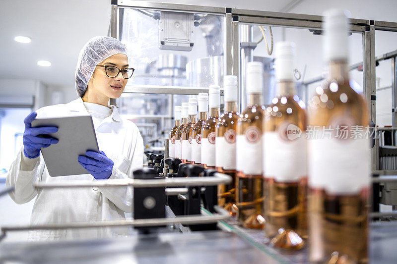 在酒精饮料装瓶厂控制葡萄酒生产的女技术人员。