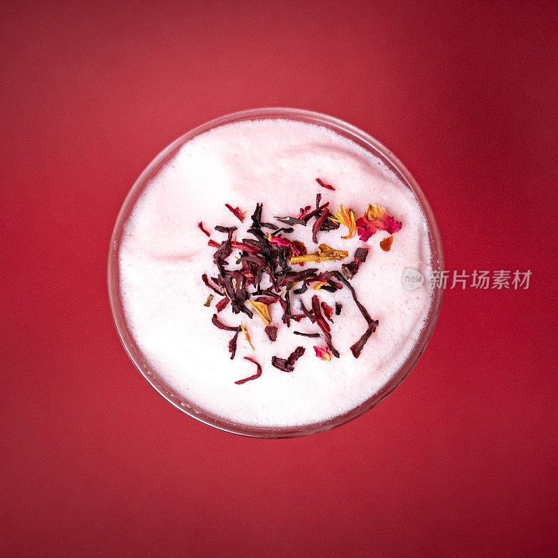 Topview的杯子与泡沫与干茶叶在一个深红色孤立的背景上