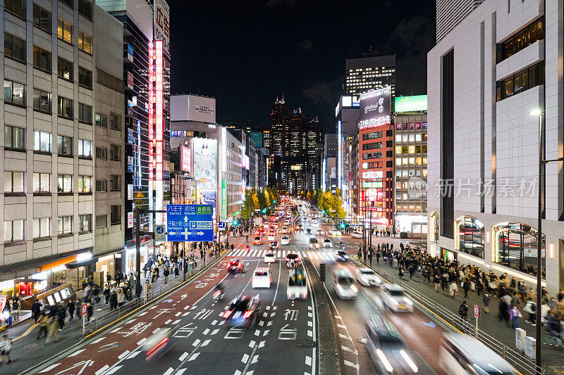 夜间运动模糊的汽车交通运输在十字路口，日本人走在日本东京新宿的十字路口，办公大楼的城市景观。亚洲交通，亚洲城市生活理念