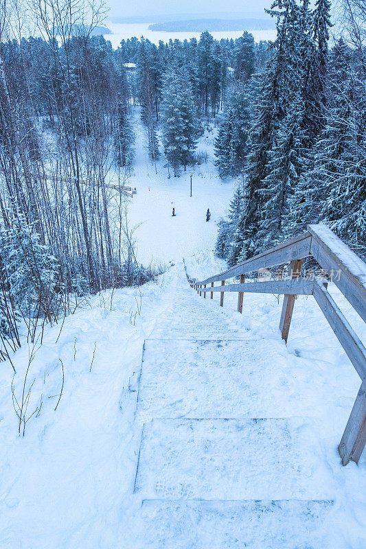 芬兰冬季自然景观，白雪覆盖的森林，高山和通往观景台的木楼梯