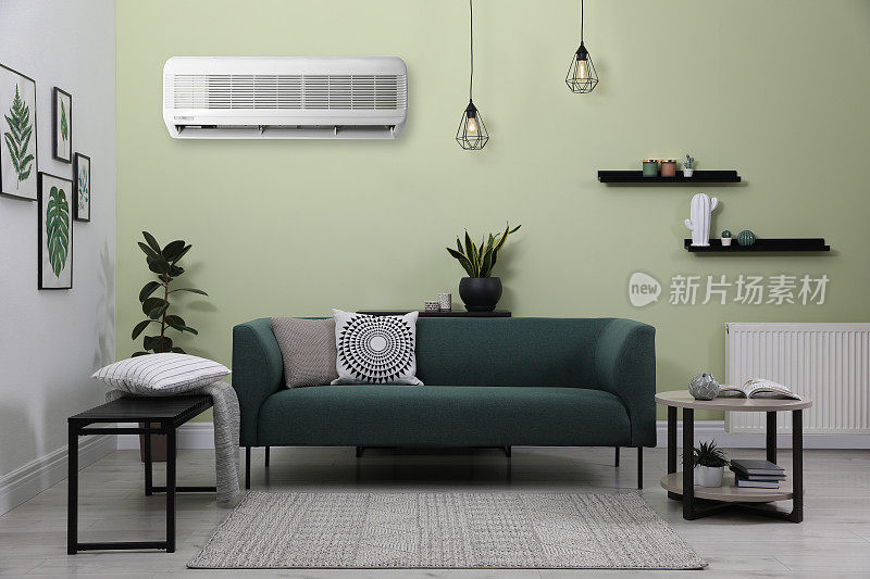 客厅淡绿色墙壁上的现代空调，时尚的家具