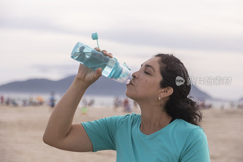 一个拉丁女人在海滩上喝水