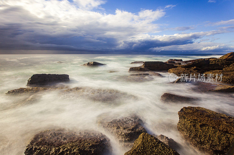 海浪和岩石长时间曝光海景与戏剧性的天空