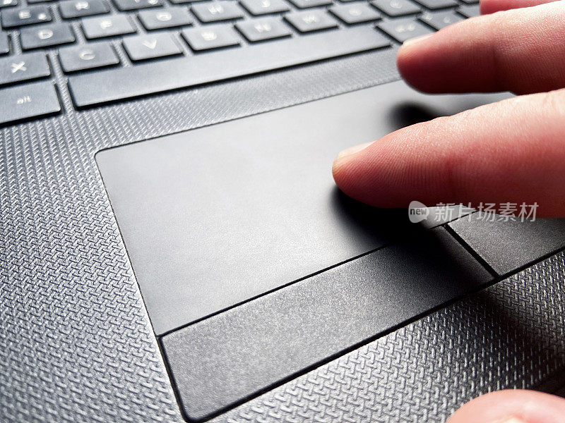 手使用笔记本电脑，人的手指在笔记本电脑的触摸板上，使用笔记本电脑