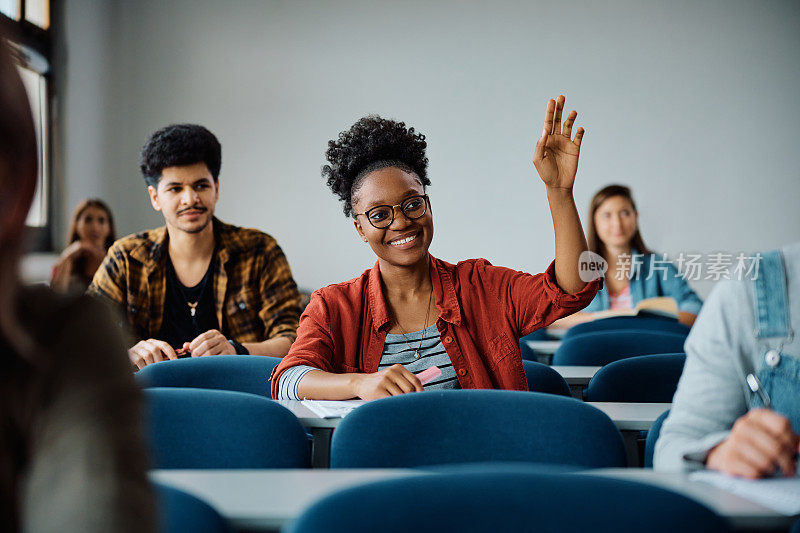 在一所大学的课堂上，一个快乐的黑人学生举手提问。