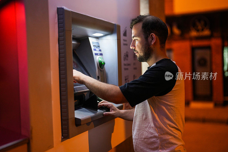 一名男子在晚上插入他的银行ATM卡取钱