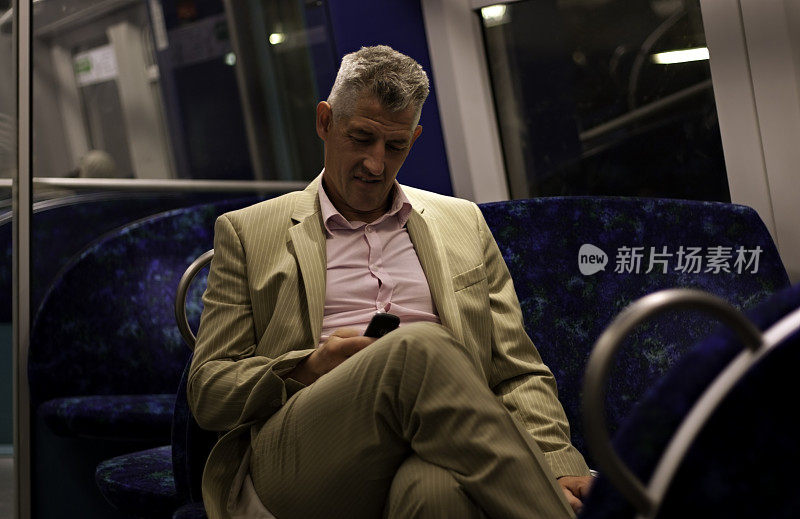 一个男人坐在火车上，看他的手机