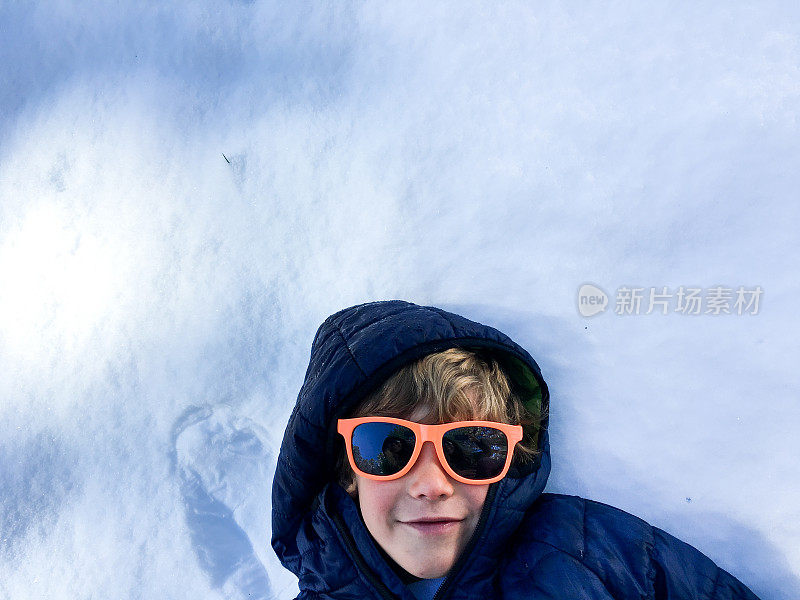 男孩在雪地里放松，看着摄像机