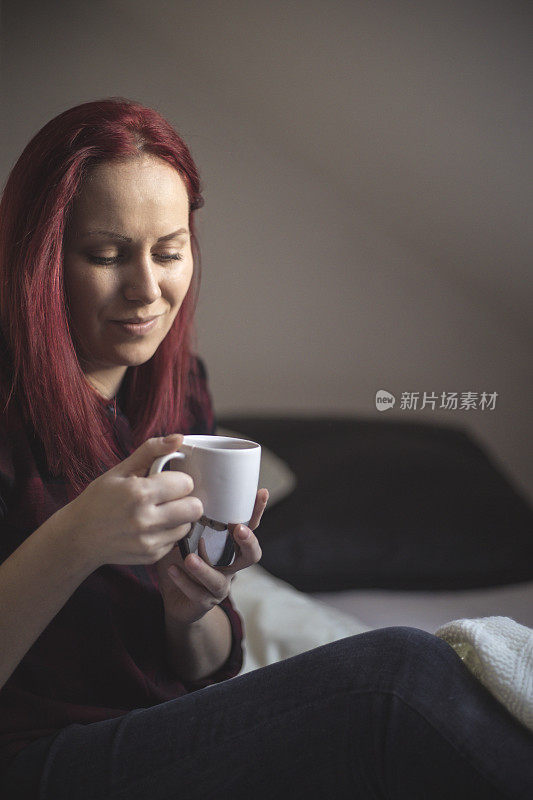 年轻女子在床上悠闲地喝着茶