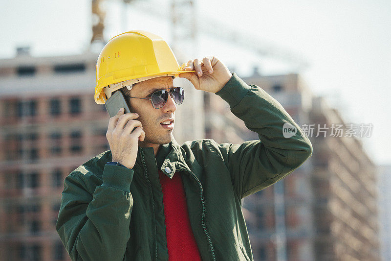 建筑工地的工程师在用智能手机通话