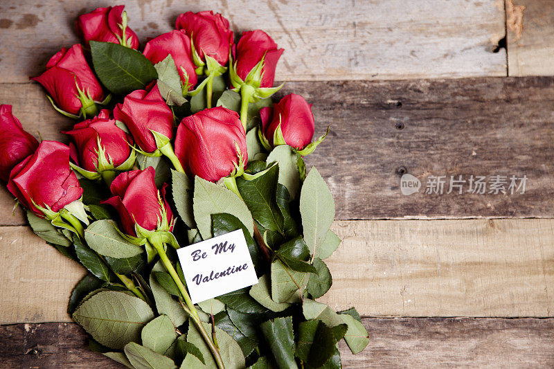 情人节。红玫瑰花束，卡片。乡村的木桌上。