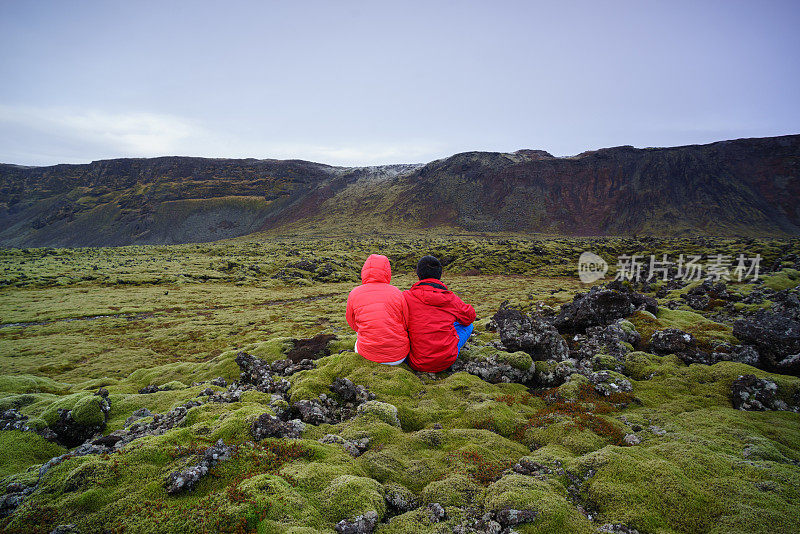 一对夫妇坐在冰岛的火山岩上