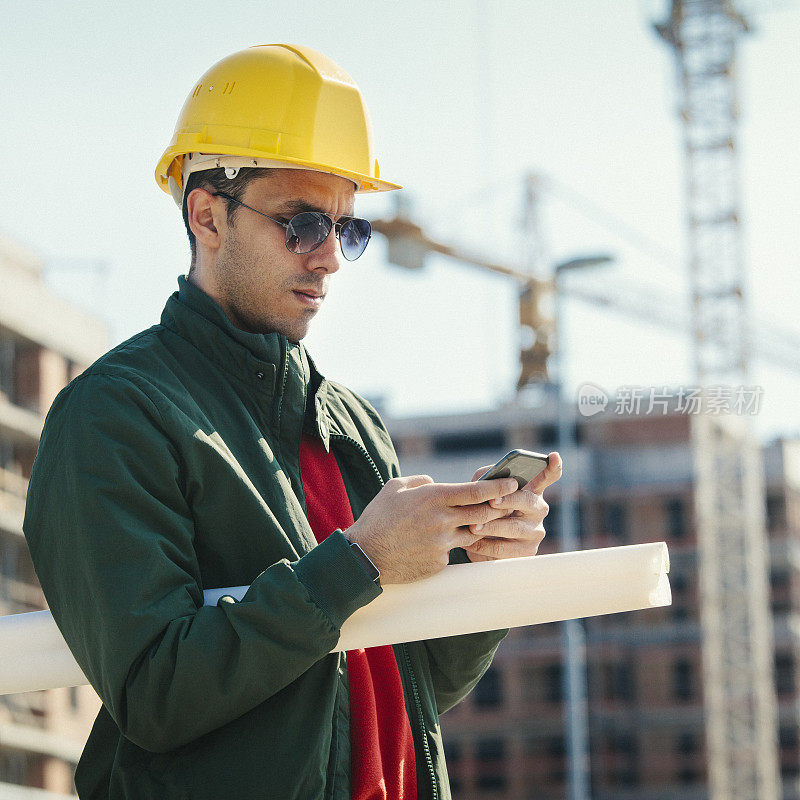 年轻工程师在建筑工地使用智能手机