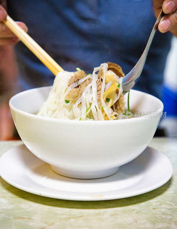 用勺子和筷子混合新鲜越南河粉汤
