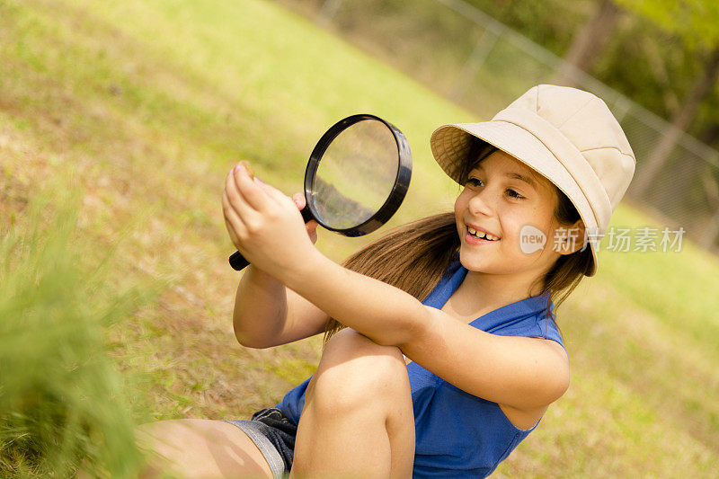 教育:可爱的小女孩在公园里拿着放大镜。科学。