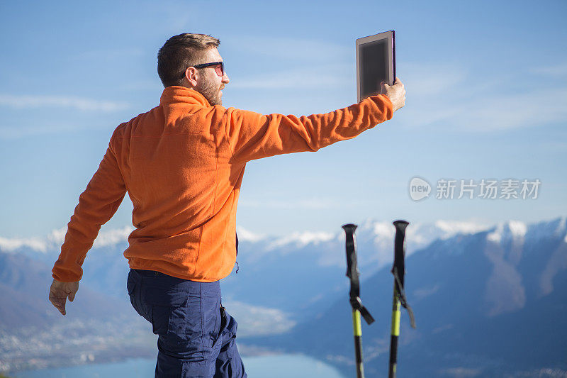 一名年轻人在山顶用平板电脑自拍