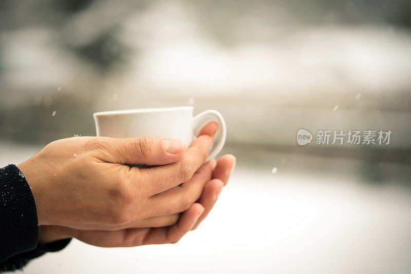 在雪中捧着热咖啡