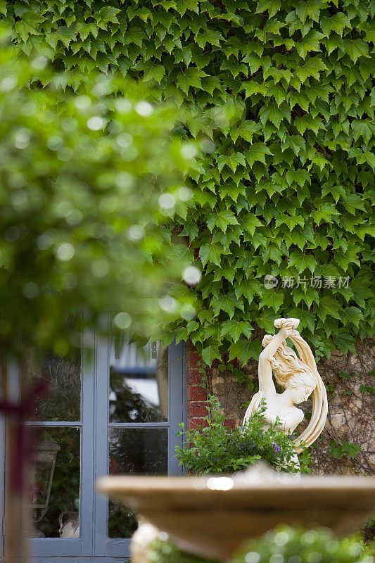 宁静的雕像矗立在郁郁葱葱的绿色花园里