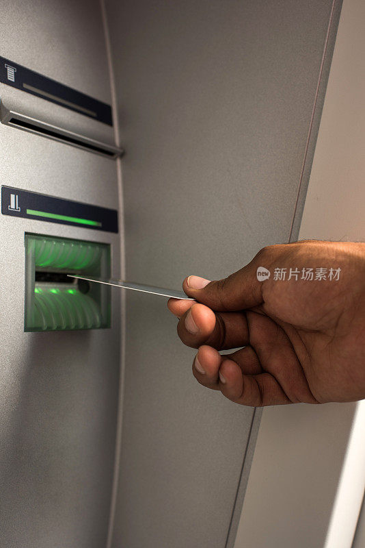 在自动取款机上使用信用卡的人的特写。