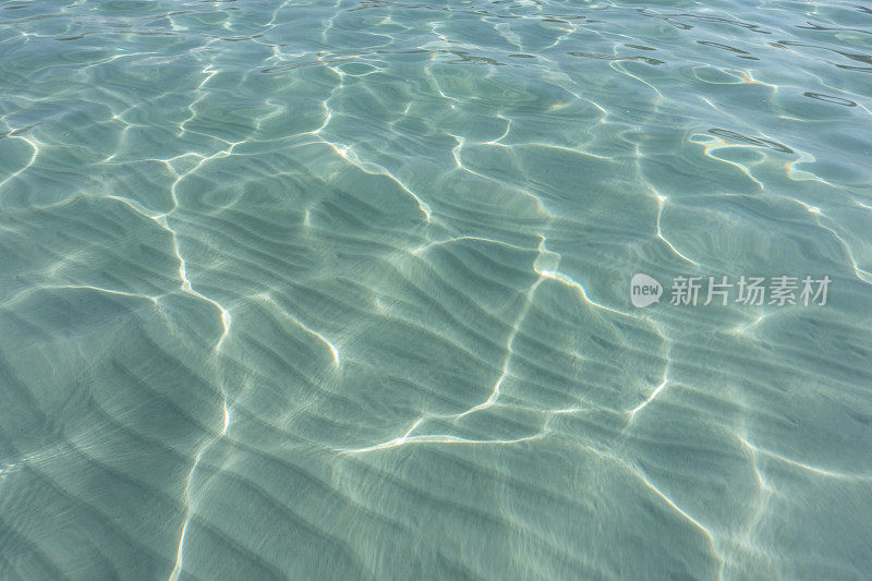 近景海水清澈，沙滩上的涟漪水在阳光下反射