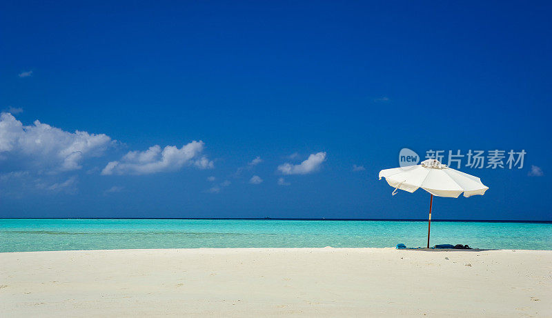 伞在田园诗般的热带沙滩上。白色的沙滩伞和蓝色的天空。海滩上的阳光和雨伞。夏日海滩景观。