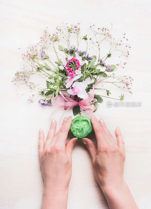 女性双手握着天然手工制作的绿色草本花卉香皂
