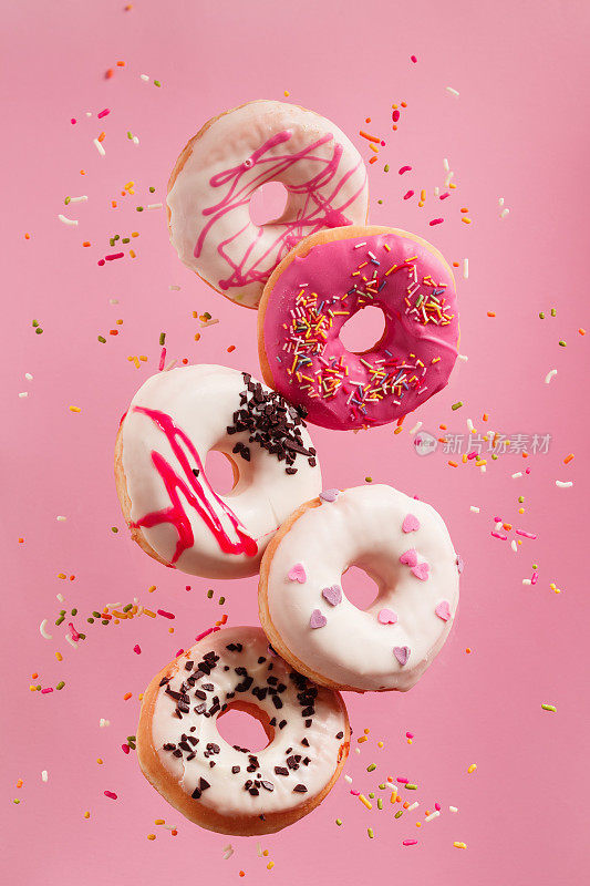 各种装饰甜甜圈的运动落在粉红色的背景。