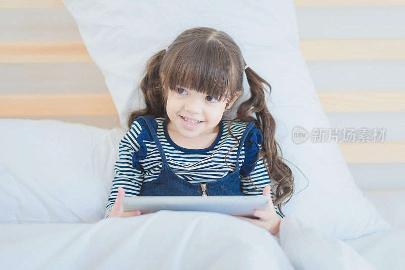 可爱的小女孩喜欢在智能平板电脑上看动画片